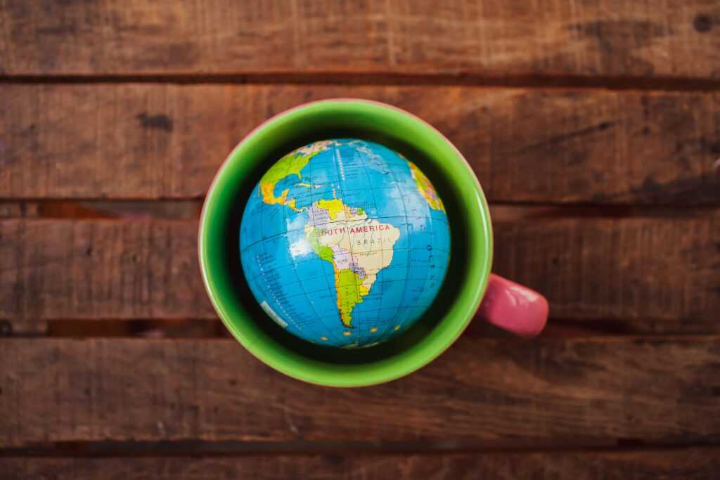 A vibrant globe in a green mug resting on a rustic wooden table.
